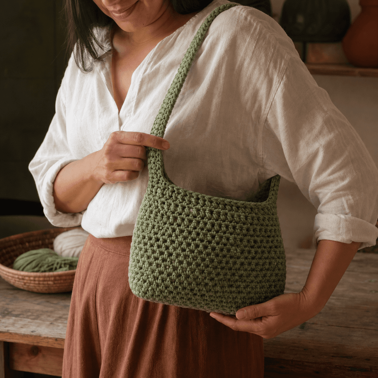 Mujer sosteniendo un bolso pequeño de crochet verde salvia